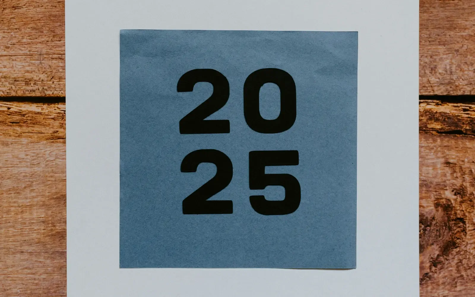 The number 2025 printed on a blue piece of paper lying on a wooden table