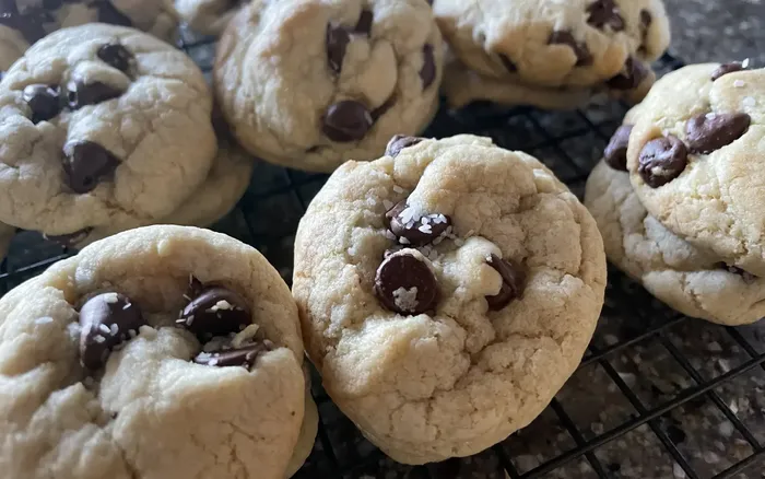 A bunch of freshly baked chocolate chip cookies sitting on a cooling rack