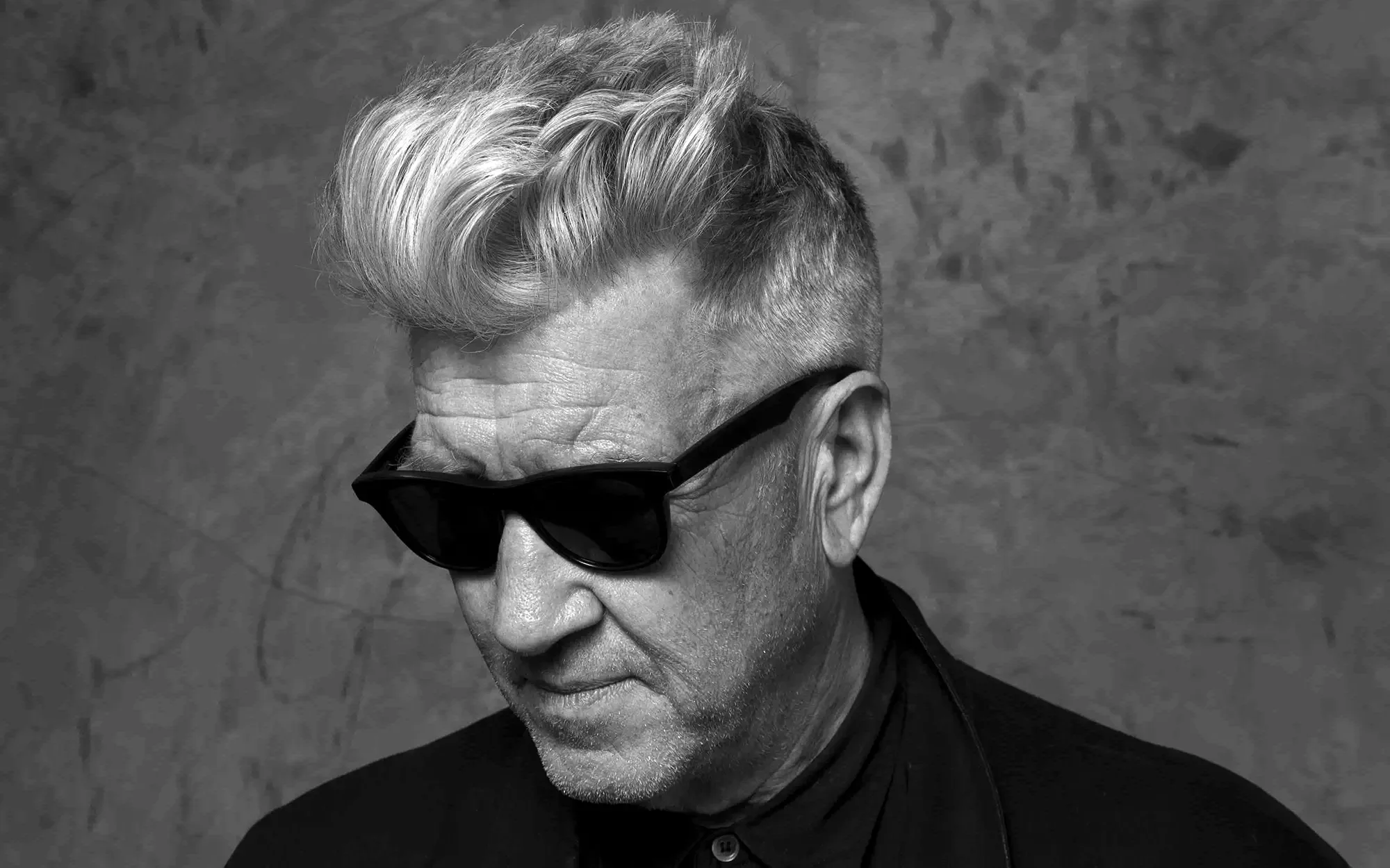 A black and white photo of David Lynch wearing sunglasses