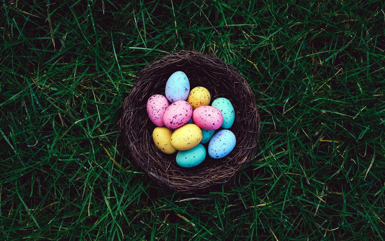 A basket of colorful easter eggs in the grass