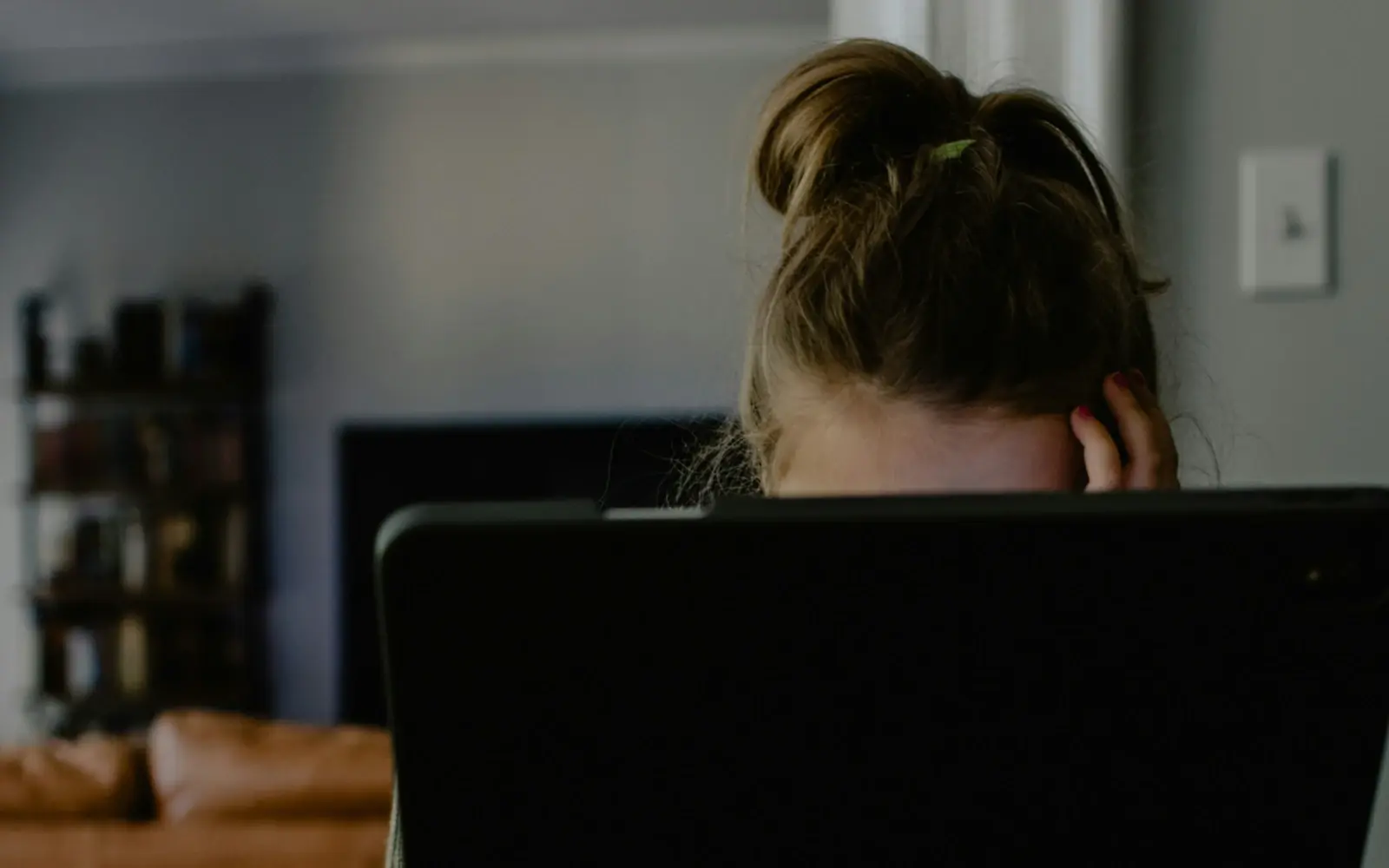 A woman with her head in her hand looks at a tablet