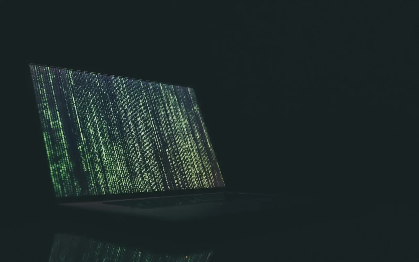 A murky photo of a laptop with strange code appearing on its screen