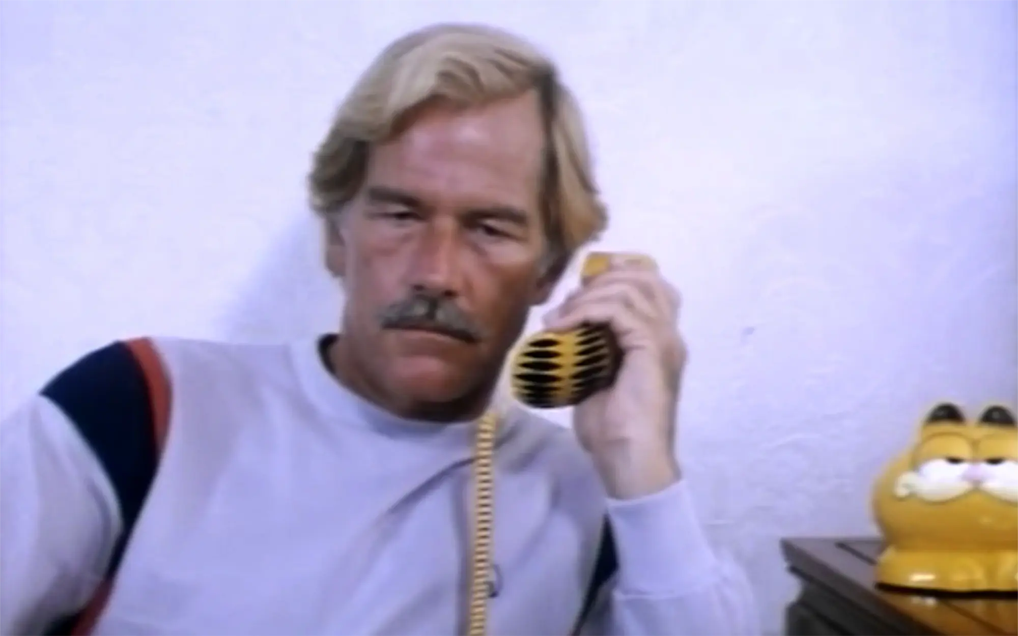 A still from Ninja Terminator featuring Richard Harrison talking on a Garfield telephone